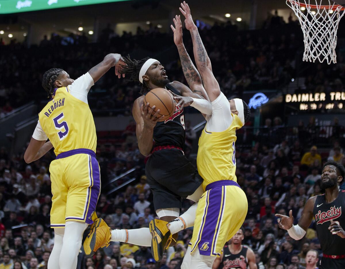 Lakers forward Anthony Davis, right, defends Trail Blazers forward Jerami Grant, center, along with teammate Cam Reddish.