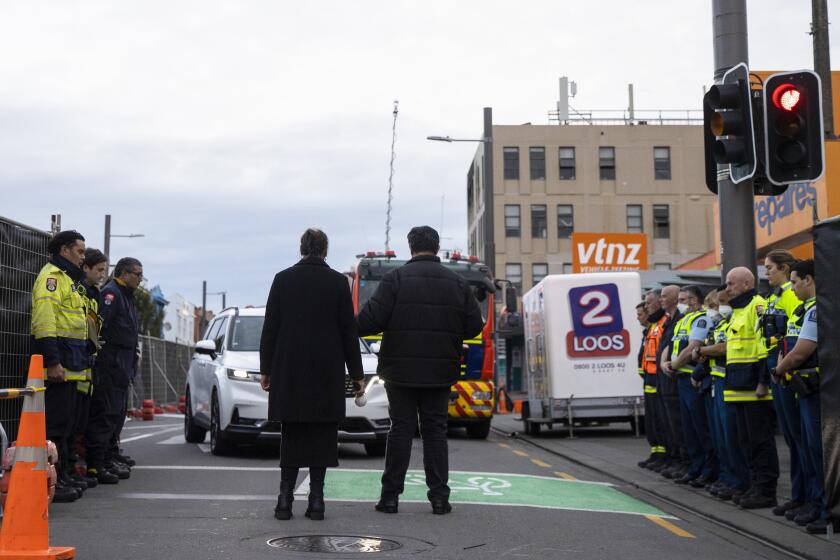 Fire and police investigators form a guard of honour as the first body is removed from the the Loafers Hostel by a hearse in Wellington, New Zealand, Thursday, May 18, 2023, following a fire that left several people dead in the early hours of Tuesday May 16. New Zealand police started removing bodies from the Wellington hostel where multiple people were killed in Tuesday's fire. (George Heard/New Zealand Herald via AP)