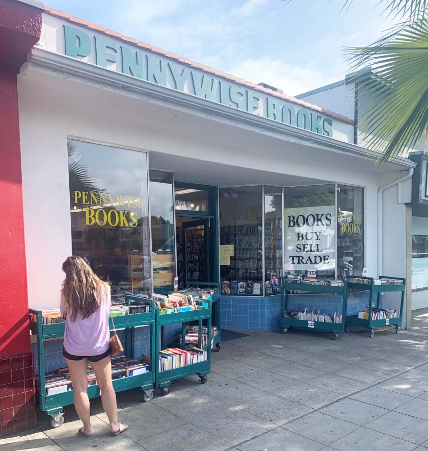 A shopper considers her choices among the five carts of $1 books available from Pennywise Books in Pacific Beach.