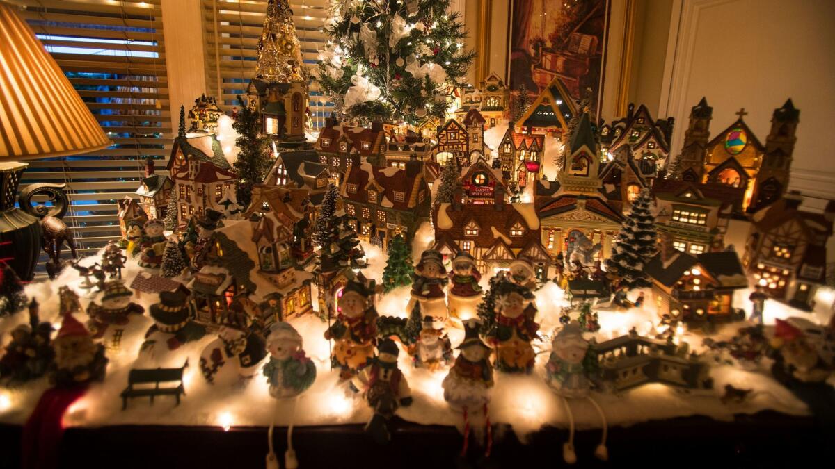 A Christmas village displayed atop a piano.
