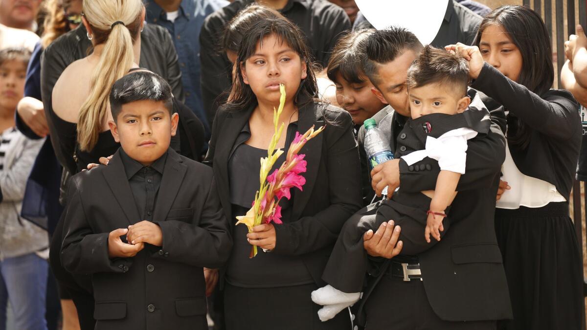 The oldest child, second from left, of Santos Hilario Garcia and Marcelina Garcia Perfecto mourns with her siblings, left, and relatives during the funeral services at Our Lady of Guadalupe Church in Delano.