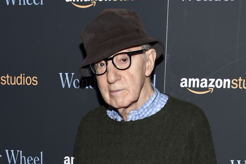 Woody Allen wearing glasses, a sweater and a hat