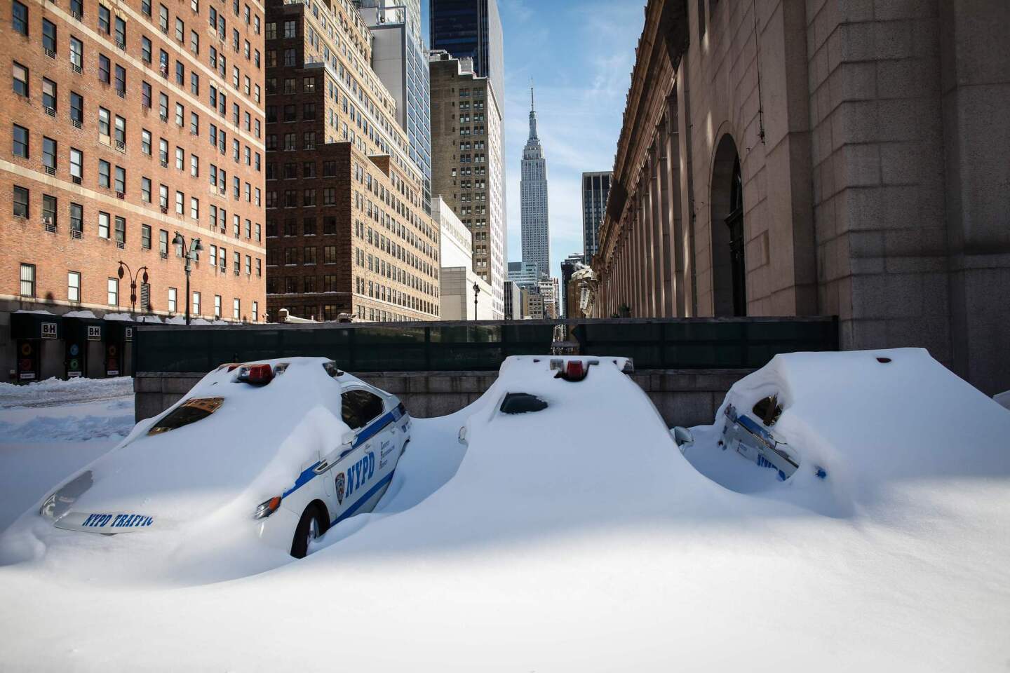 NYPD cars covered in snow are seen in New York. Millions of people in the eastern United States started digging out from a huge blizzard that brought New York and Washington to a standstill, but the travel woes were far from over.