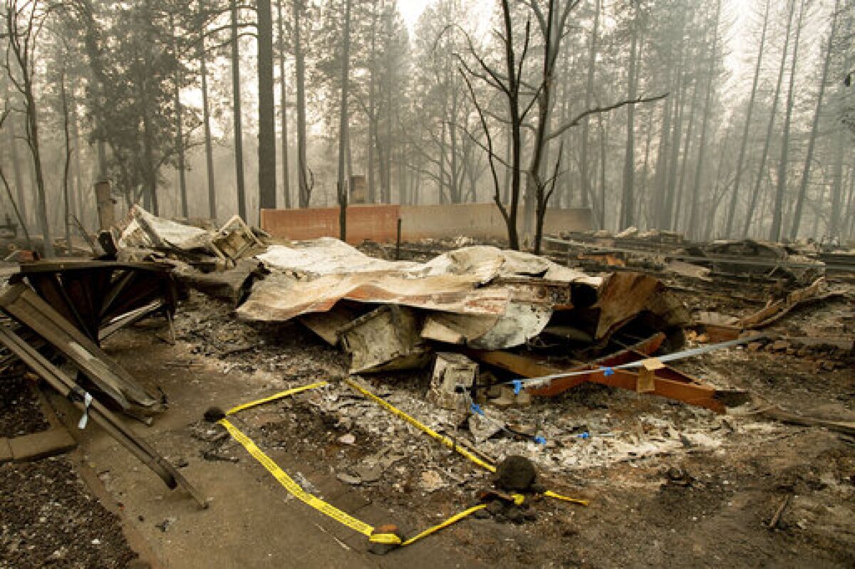 Tape marks a spot where sheriff's deputies recovered the body of a Camp fire victim in Paradise, Calif., last year. 