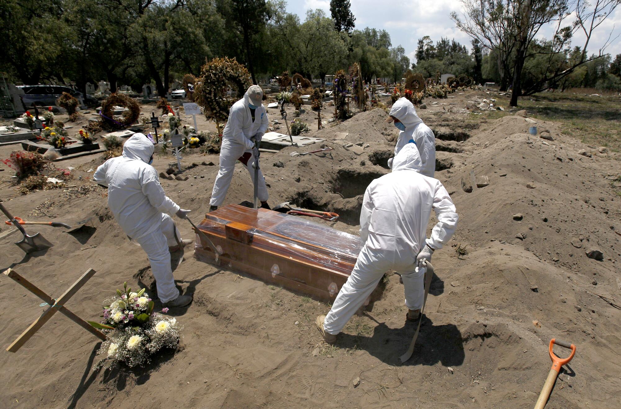 Cemetery workers in a protective gear lower the coffin of a COVID-19 victim into the ground in Mexico City.