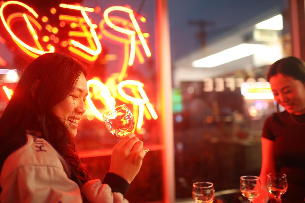 Two patrons laugh over glasses of wine