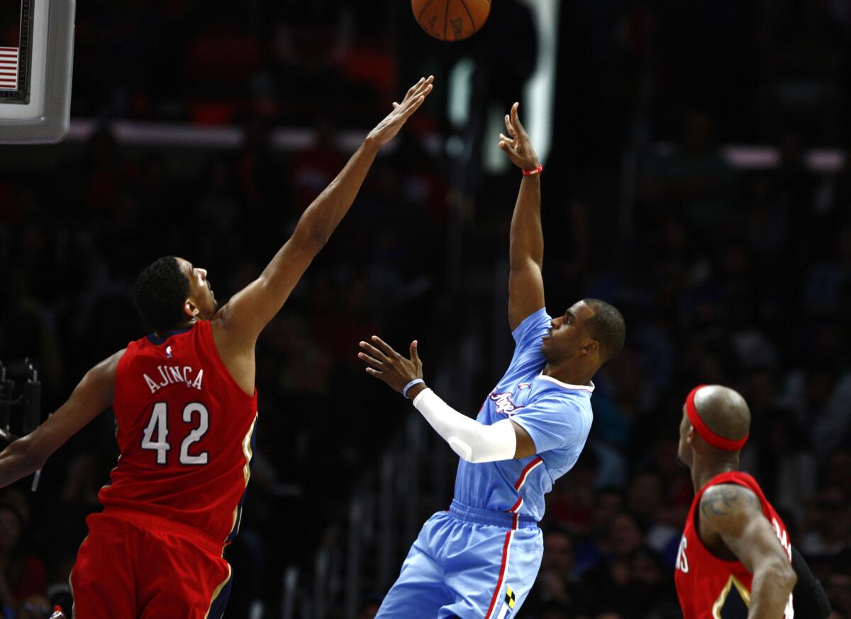 Clippers guard Chris Paul shoots while under pressure from New Orleans center Alex Ajinca on March 22.