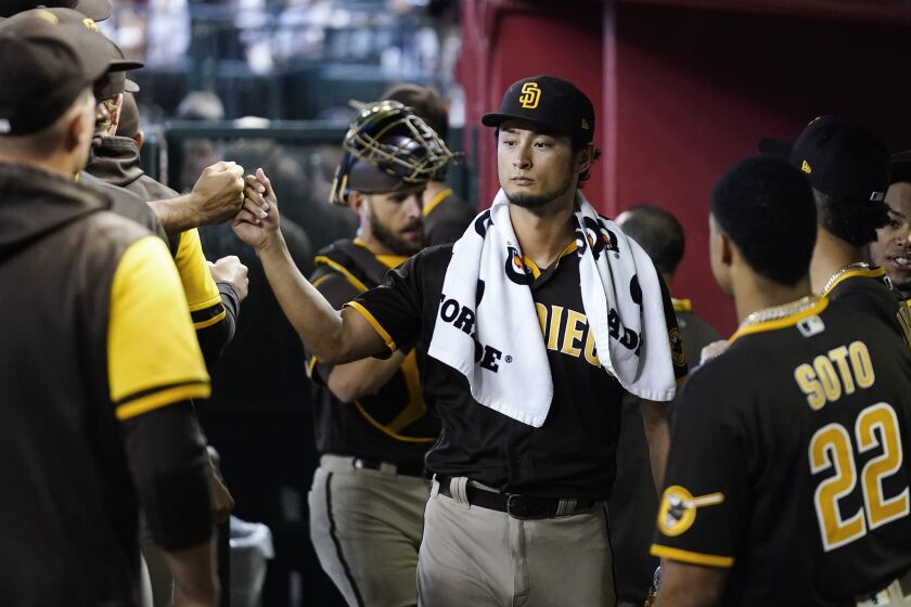 San Diego Padres starting pitcher Yu Darvish, of Japan, gets fist-bumps from teammates in the dugout prior to a baseball game against the Arizona Diamondbacks in Phoenix, Sunday, Sept. 18, 2022. (AP Photo/Ross D. Franklin)