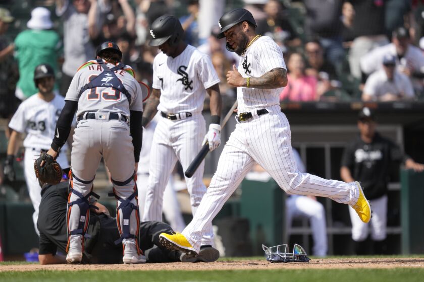 Chicago White Sox's Yoan Moncada scores the game winning run on Detroit Tigers relief pitcher Jose Cisnero's wild pitch in the 10th inning of a baseball game Saturday, June 3, 2023, in Chicago. Tigers catcher Eric Haase and Tim Anderson look after home plate umpire Cory Blaser who was knocked down on the play. The White Sox won 2-1. (AP Photo/Charles Rex Arbogast)