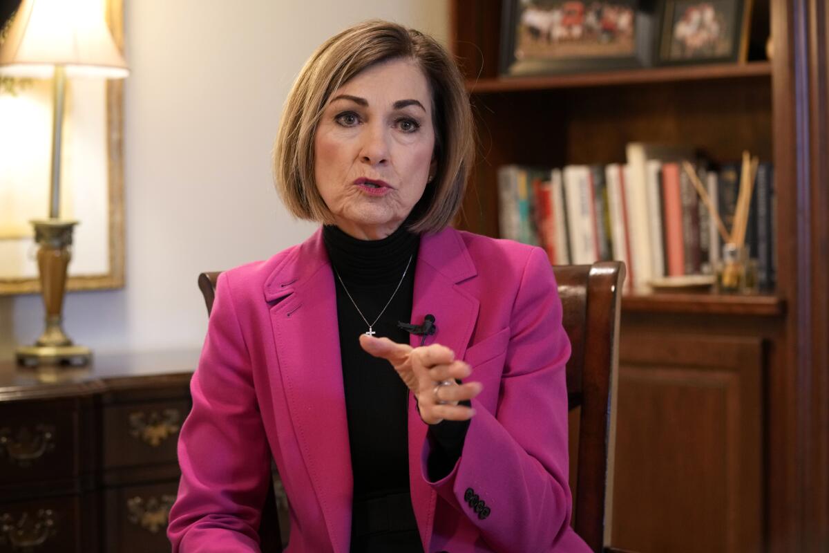 A woman talks while wearing a fuchsia jacket.
