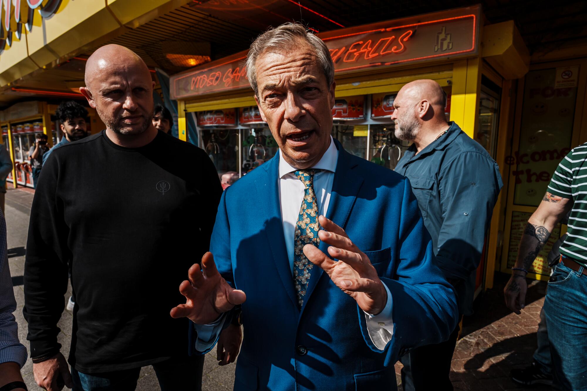 Nigel Farage gesticula em um terno azul brilhante.