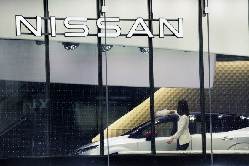 FILE - A staff of Nissan car showroom wipes a car on Jan. 31, 2022, in Tokyo. Nissan reported a 55% jump in October-December profit Thursday, Feb. 9, 2023, as the Japanese automaker seeks to embark on a less bumpy journey with its French alliance partner Renault. (AP Photo/Eugene Hoshiko, File)