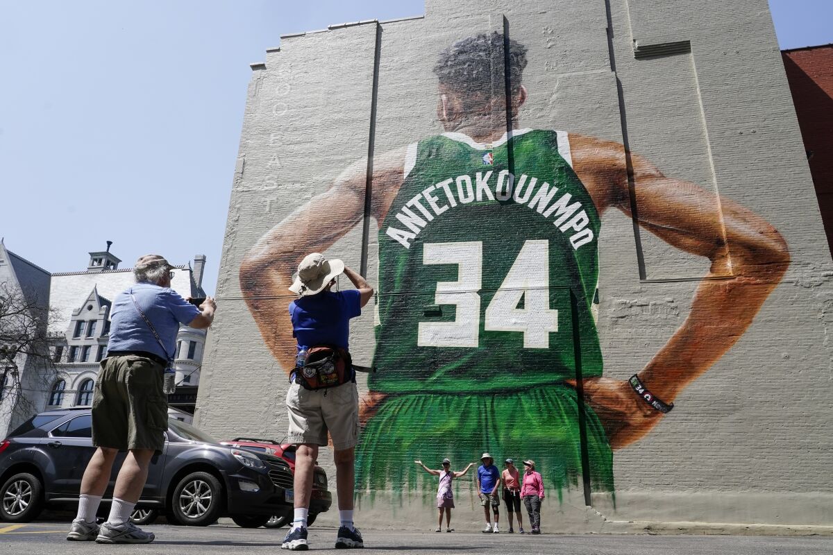 Fans take pictures of a mural of Milwaukee Bucks' Giannis Antetokounmpo painted on the side of a building Thursday, May 12, 2022, in Milwaukee. The mural will be dedicated on Friday, May 13, 2022, before Game 6 of the NBA Eastern Conference semifinal game between the Milwaukee Bucks and the Boston Celtics. (AP Photo/Morry Gash)