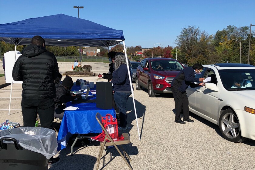 Masked people go to car windows in a parking lot