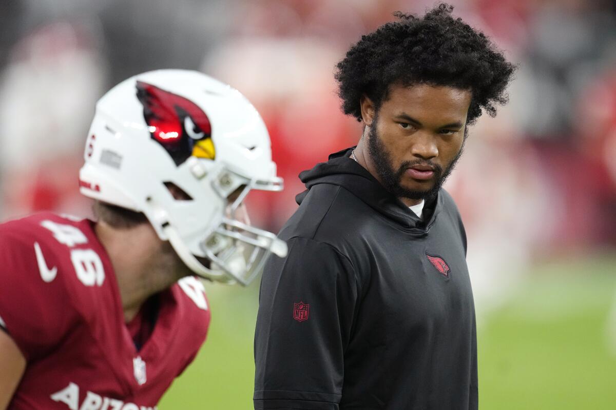 Injured Cardinals quarterback Kyler Murray talks with Cardinals long snapper Aaron Brewer.