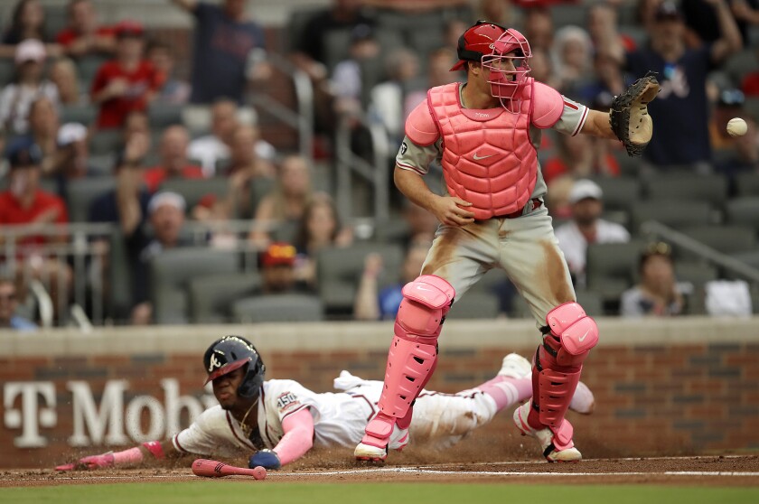Atlanta Braves' Ronald Acuna Jr. slides safe to score as Philadelphia Phillies catcher J.T. Realmuto waits for the ball in the first inning of a baseball game Sunday, May 9, 2021, in Atlanta. Acuna scored on a single by Braves' Freddie Freeman. (AP Photo/Ben Margot)