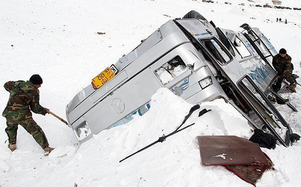 Members of the Afghan army try to remove snow from an overturned bus in the historic Salang Pass through the rugged mountains of the Hindu Kush. Authorities announced Wednesday that the death toll had risen to at least 166 in a series of avalanches that thundered down the route.