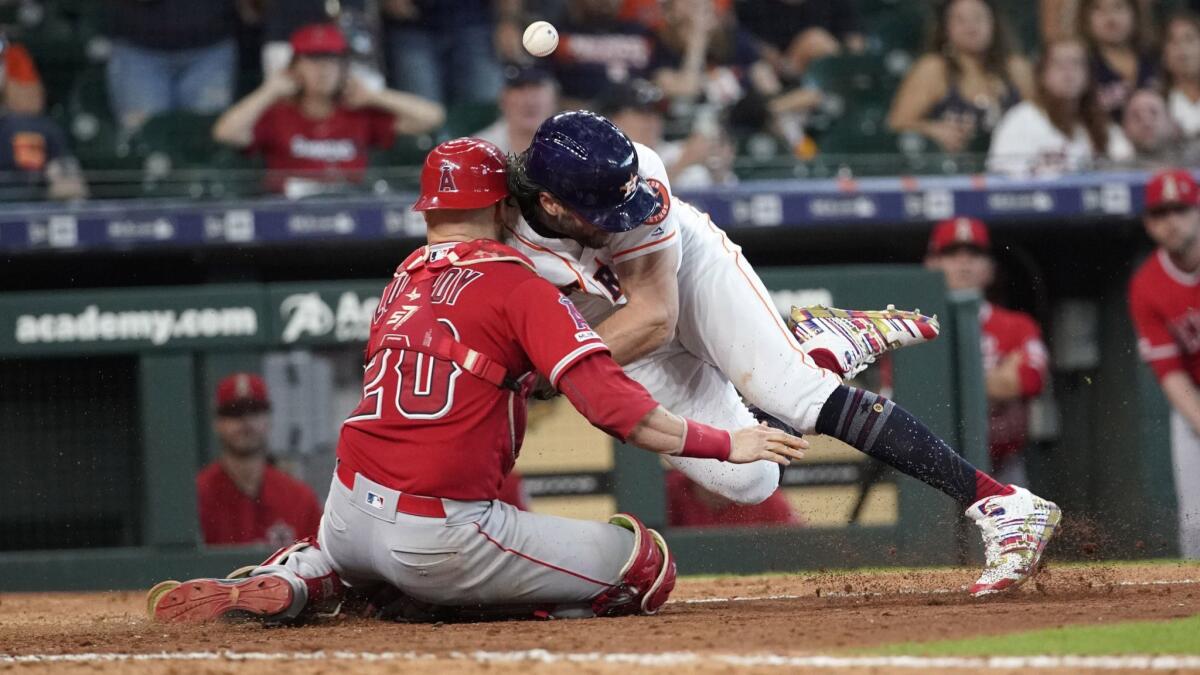 Houston Astros baserunner Jake Marisnick collides with Angels catcher Jonathan Lucroy while trying to score during the eighth inning of Sunday’s game.