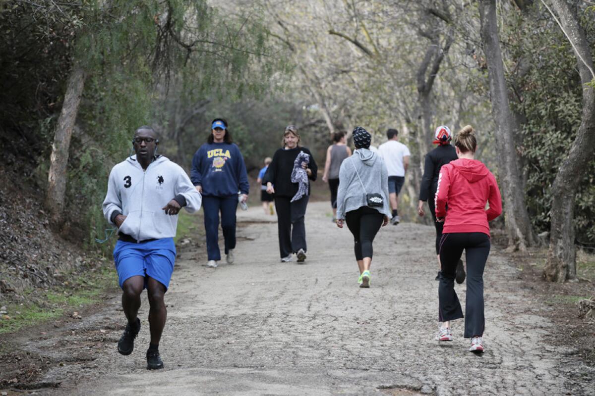 Hikers and joggers come and go at the trail head in Fryman Canyon.