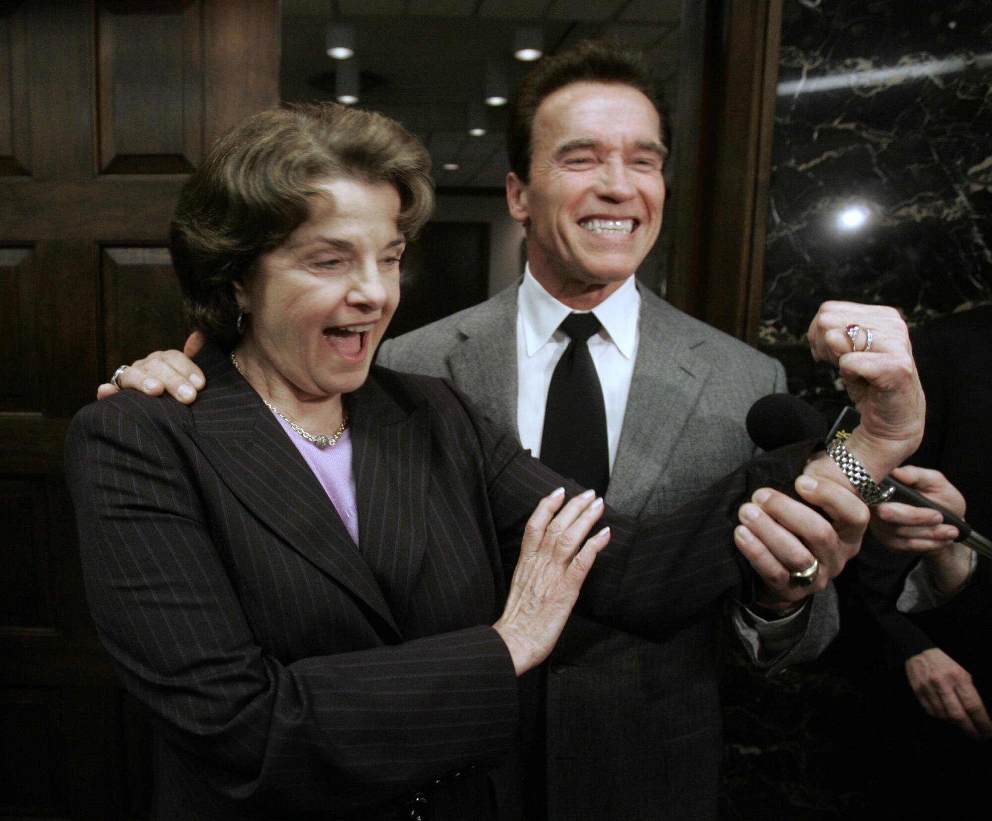With the help of Gov. Arnold Schwarzenegger, U.S. Senator Dianne Feinstein flexes her bicep 