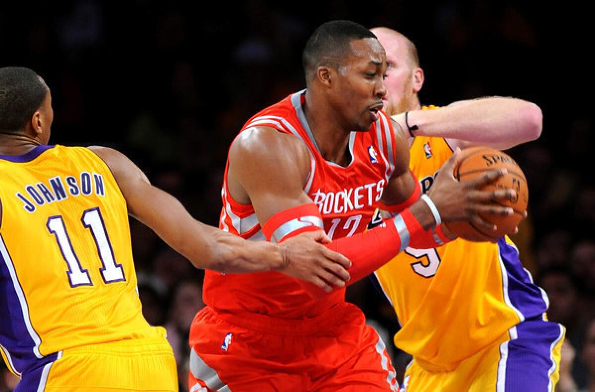Rockets center Dwight Howard splits the double-team defense of Lakers forward Wesley Johnson and center Chris Kaman on a drive to the basket in the first half Wednesday night at Staples Center.