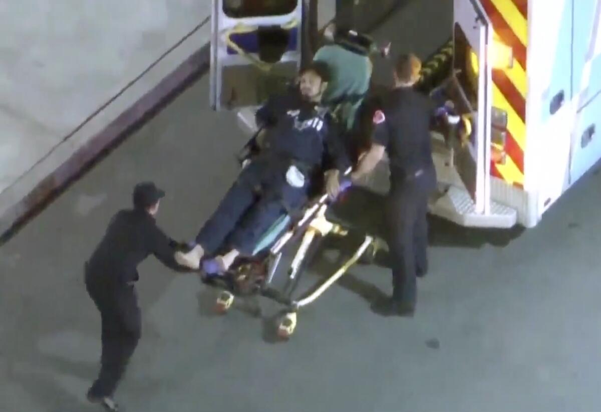 Two people put a gurney with a person on it into an ambulance.