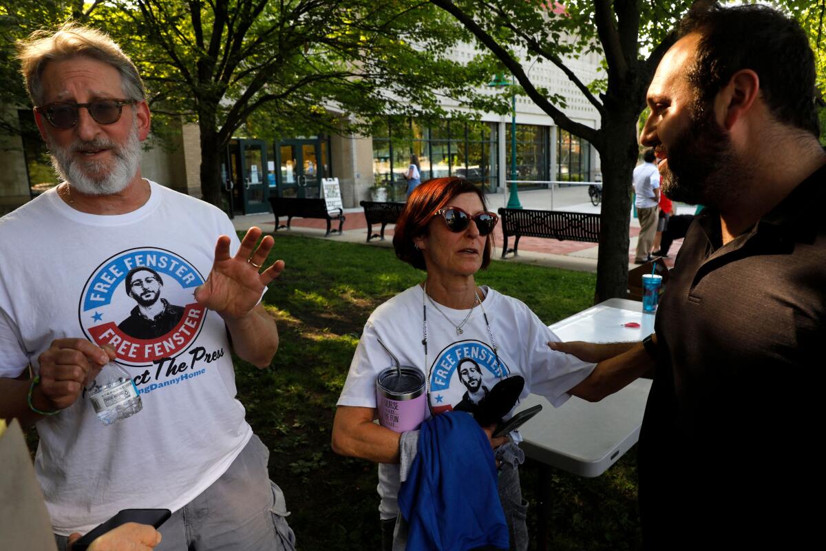 A man and woman in "Free Fenster" T-shirts speak with a supporter.