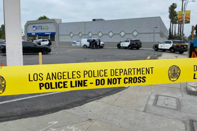 Yellow Los Angeles Police Department tape blocks off a Rite Aid parking lot, where police cruisers are parked