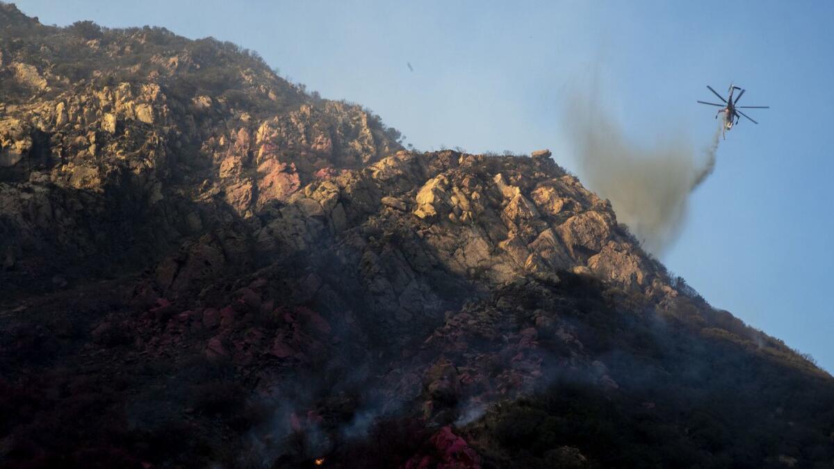 A helicopter drops water on the Woolsey fire in Malibu on Sunday.