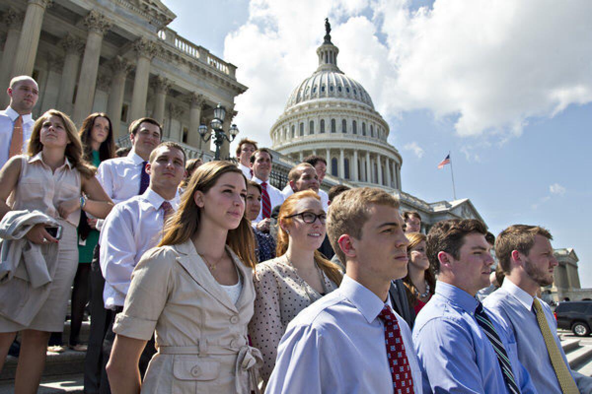 College students wait on the steps of the House of Representatives for GOP leaders to arrive for a news conference on federal student loan rates.