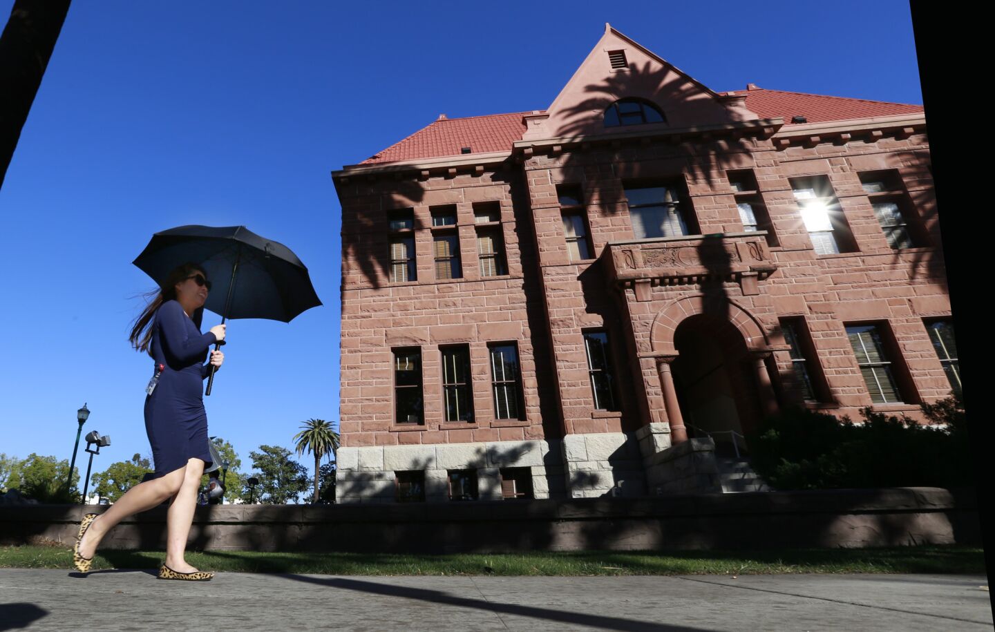 Amid high winter temperatures, a pedestrian uses an umbrella for shade outside the Old Orange County Courthouse in Santa Ana.