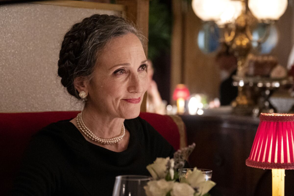 A woman at a restaurant table smiling.