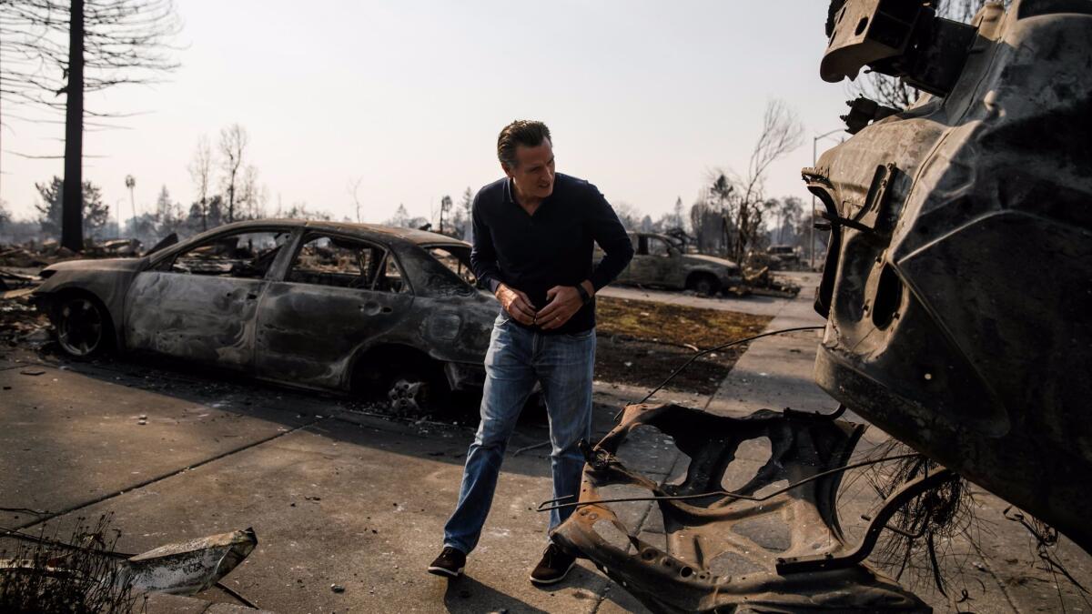 Lt. Gov. Gavin Newsom examines a charred car that was flipped upside down during the wildfire in Santa Rosa's Coffey Park neighborhood.