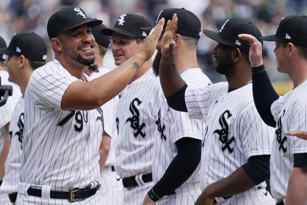 Chicago White Sox's Jose Abreu, left, greets teammates as he runs on the field during an opening day baseball game against the Seattle Mariners in Chicago, Tuesday, April 12, 2022. (AP Photo/Nam Y. Huh)