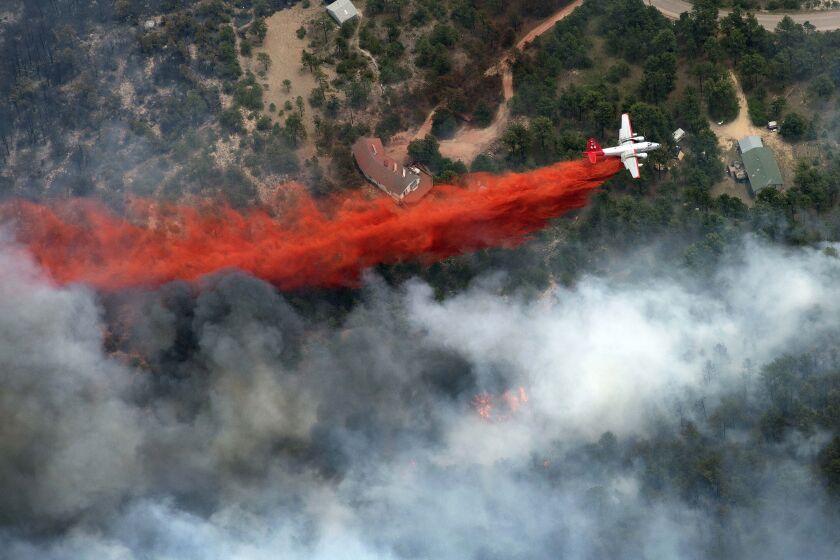 FILE - An aircraft lays down a line of fire retardant between a wildfire and homes in the dry, densely wooded Black Forest area northeast of Colorado Springs, Colo., on June 13, 2013. A federal judge said Friday, May 26, 2023, that chemical retardant dropped on wildfires by the U.S. Forest Service is polluting streams in western states in violation of federal law, but said it can keep being use to fight fires. (AP Photo/John Wark, File)