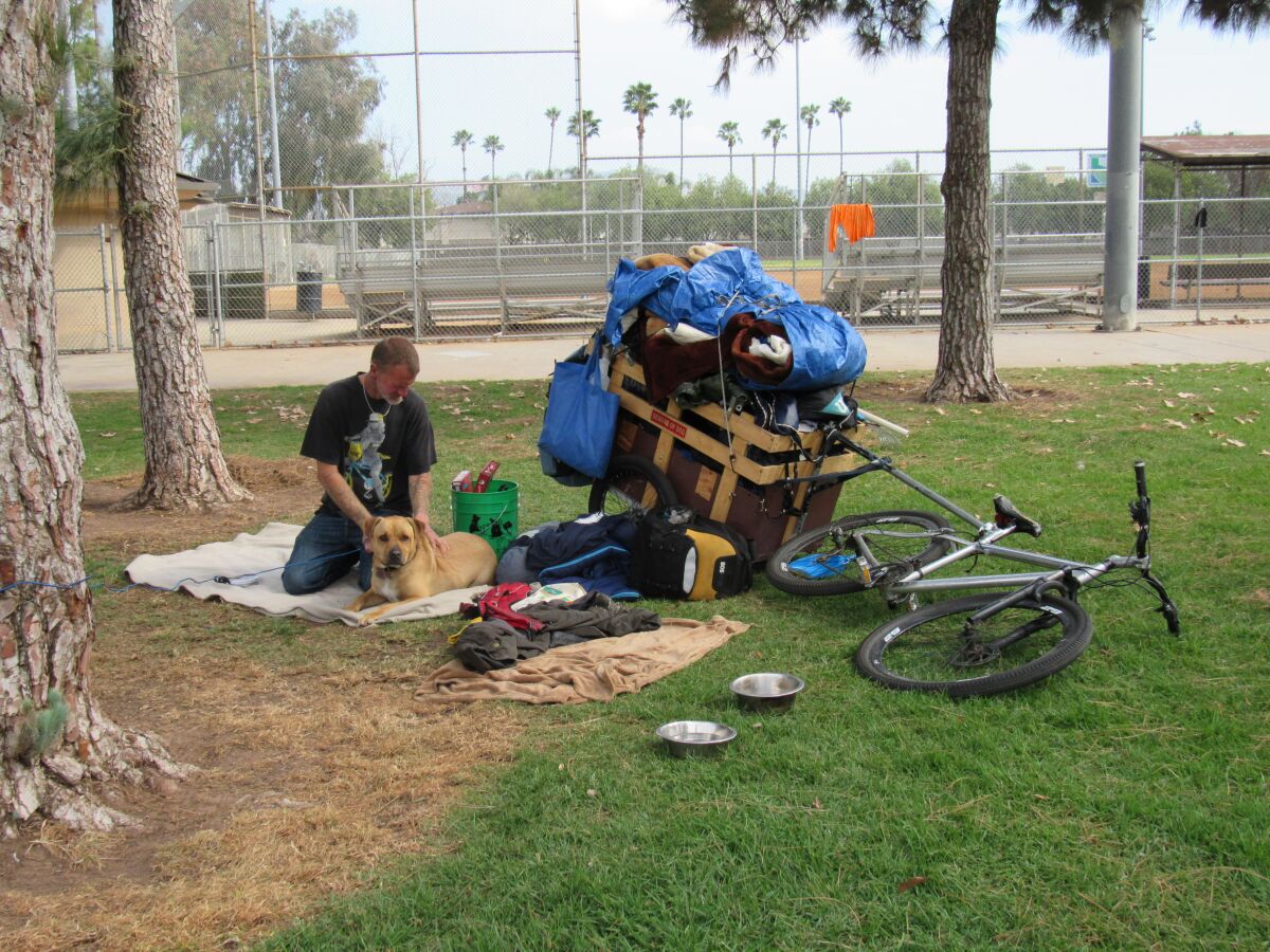 A homeless man with his dog and many possession at Wells Park in El Cajon. 