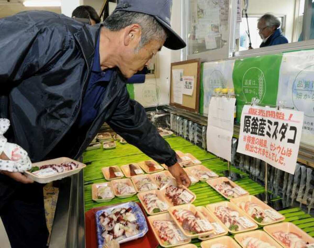 A shopper chooses packs of octopus caught in the waters off Fukushima at a supermarket in Soma, Japan.