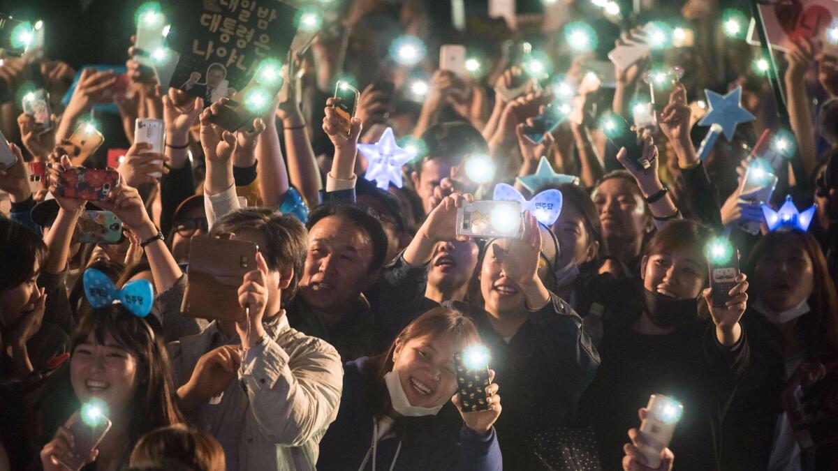 Supporters cheer as South Korean presidential candidate Moon Jae-in greets them after exit polls suggested a landslide victory, on a stage in the central Gwanghwamun district of Seoul on May 10, 2017.