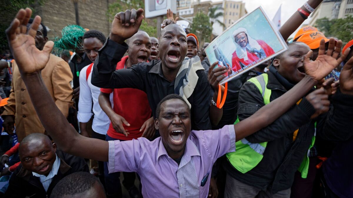 Supporters of opposition leader Raila Odinga, including one carrying a poster of Supreme Court Chief Justice David Maraga, demonstrate outside the Supreme Court in downtown Nairobi.