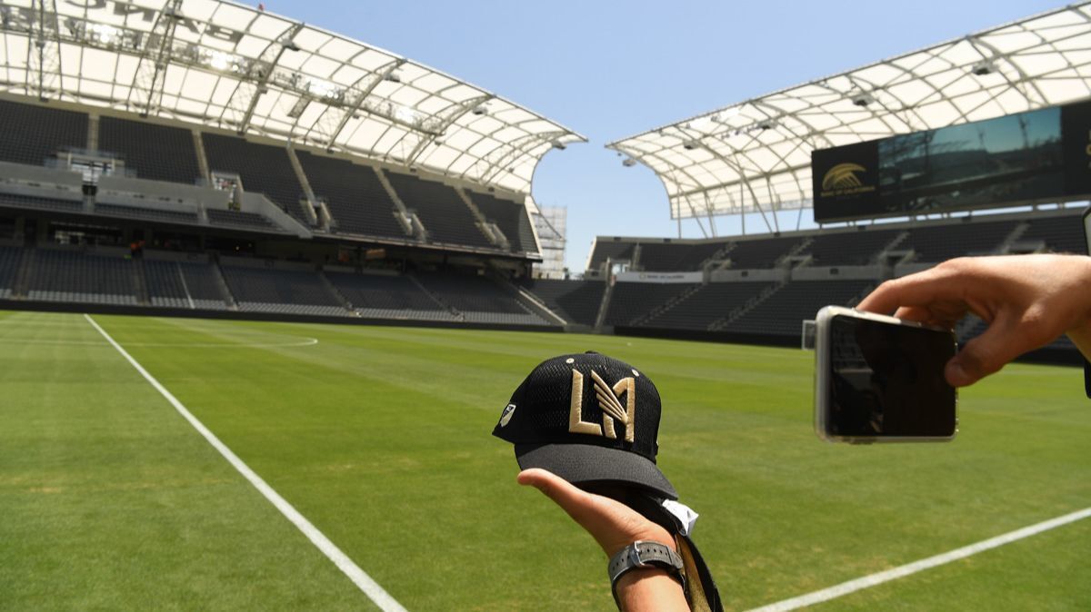 A fan holds a hat for a picture inside the LAFC soccer stadium after opening ceremonies in Los Angeles on Wednesday.