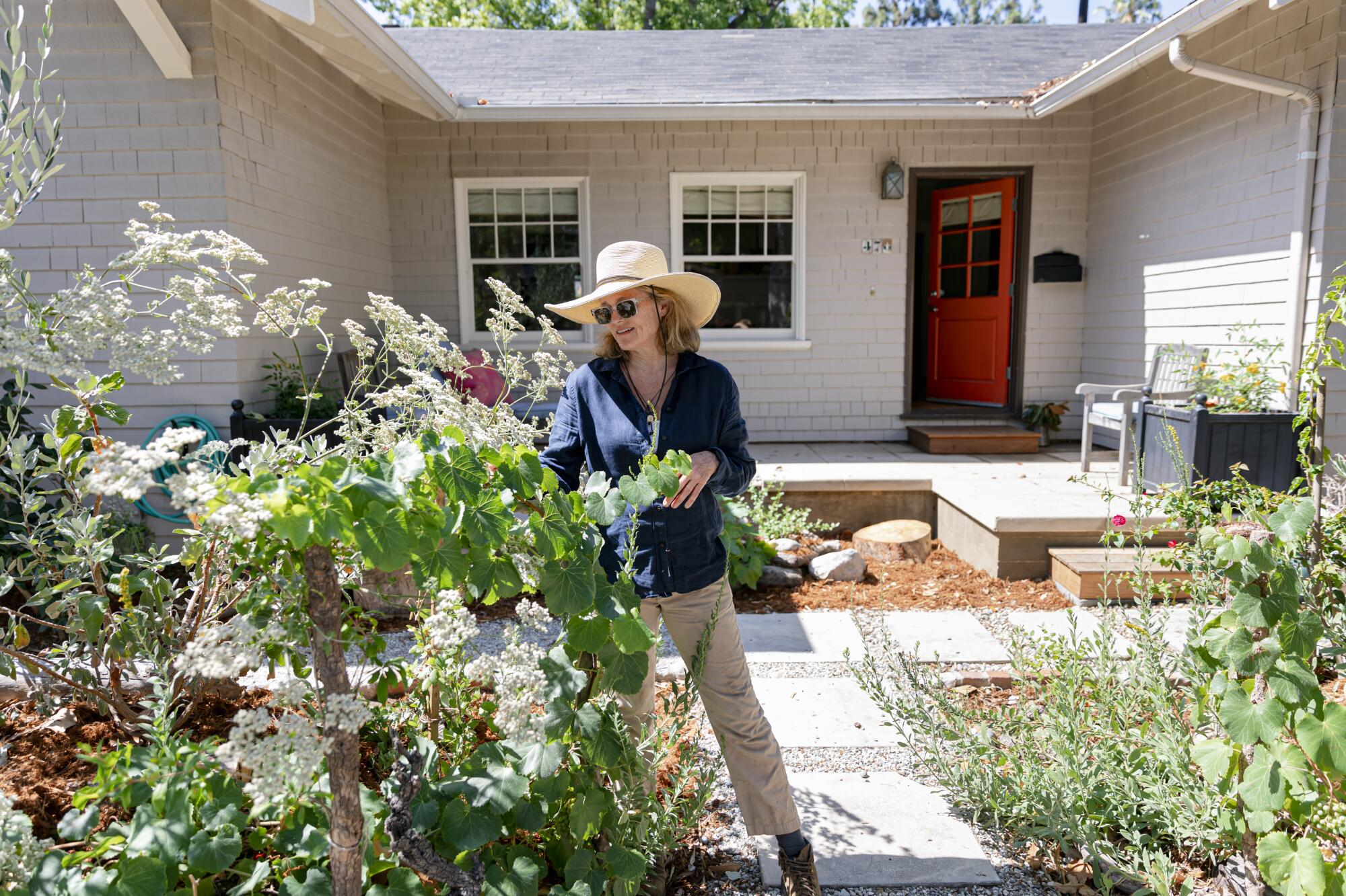 A woman tends to plants outside a house.
