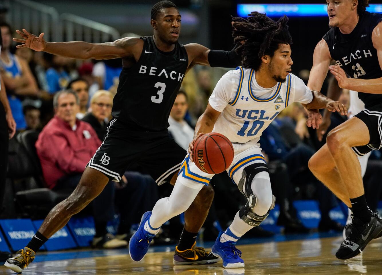 UCLA guard Tyger Campbell (10) dribbles the ball while being defended by Long Beach State guard Drew Cobb (3) and forward Romelle Mansel (13) during the first half of game Nov. 6 at Pauley Pavilion.