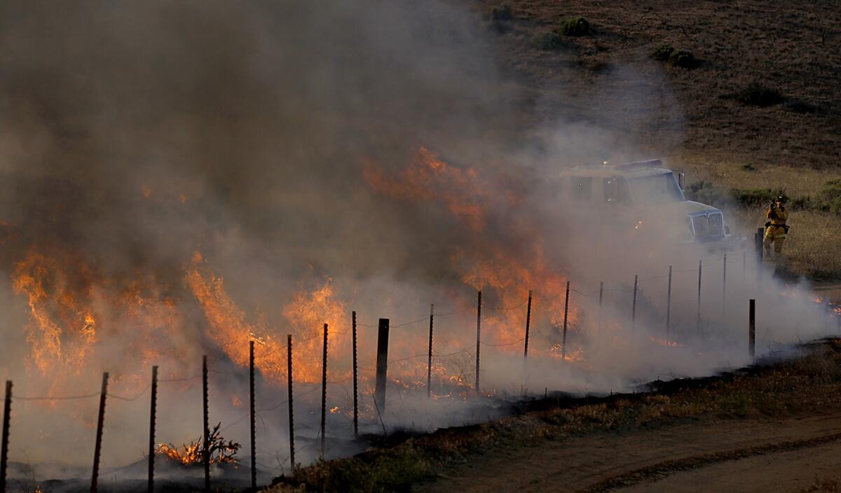 The Grand fire burns along a road in Hungry Valley State Park as firefighters battle the blaze.