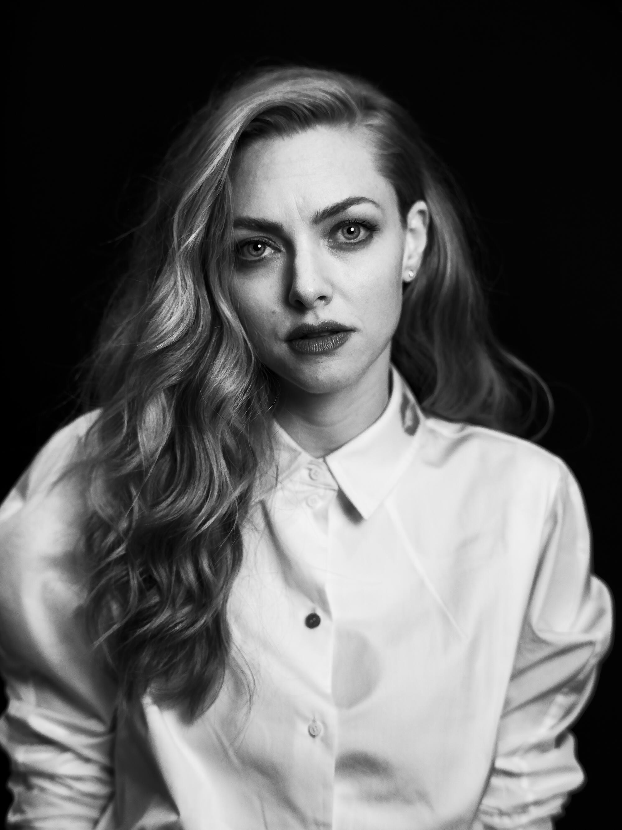 A woman in a white collared shirt poses in front of a black background