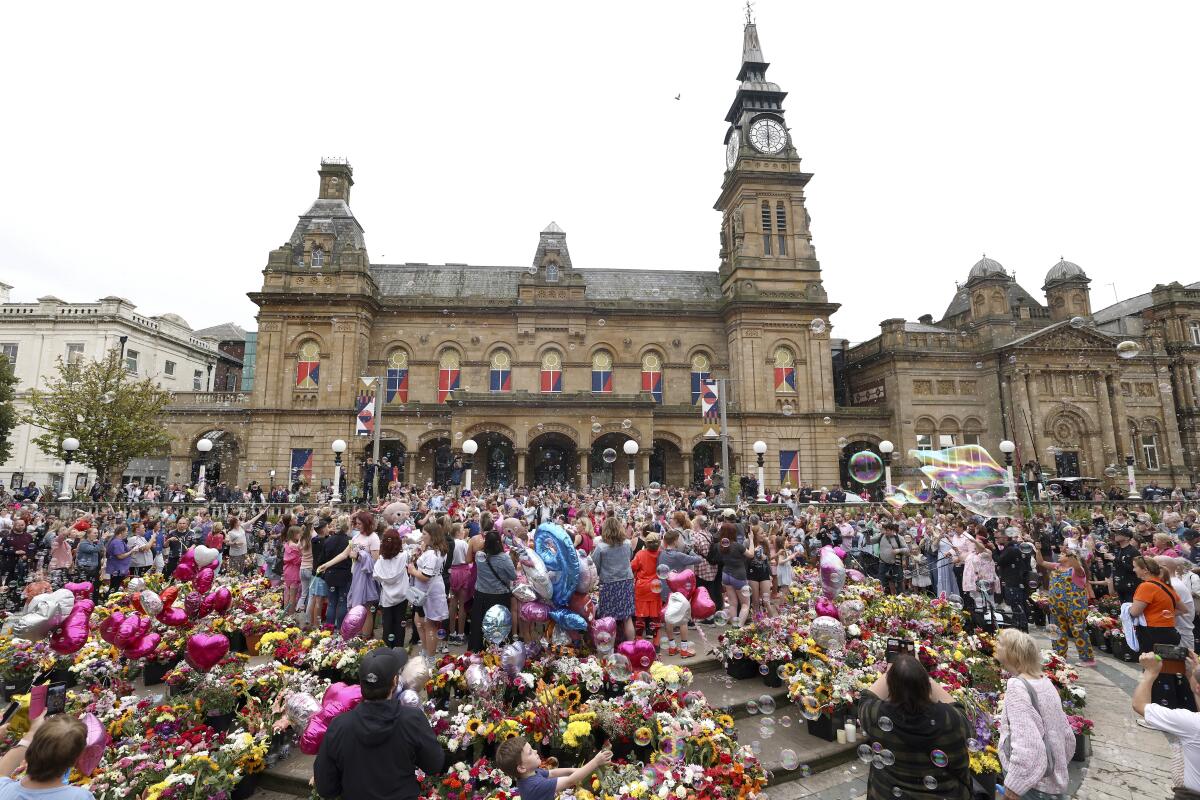 Members of the public gather outside the Town Hall in Southport, England, during a vigil for the victims of stabbing attack.