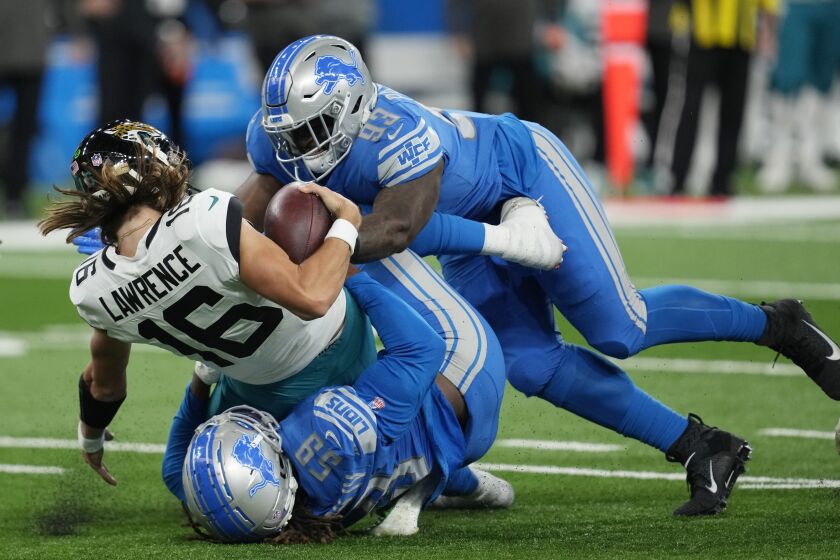 Jacksonville Jaguars quarterback Trevor Lawrence (16) is sacked by Detroit Lions linebacker James Houston (59) and defensive end Josh Paschal (93) during the first half of an NFL football game, Sunday, Dec. 4, 2022, in Detroit. (AP Photo/Paul Sancya)