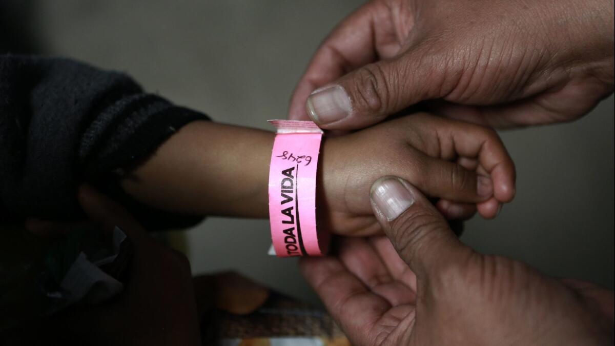A child wears a bracelet marked with a number indicating his place in line to submit a request for U.S. asylum inside a shelter in Ciudad Juarez, Mexico on Feb. 19.