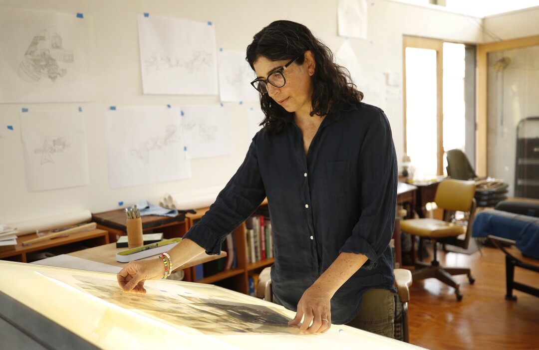 Kim Schoenstadt reviews papers on a light table in her studio