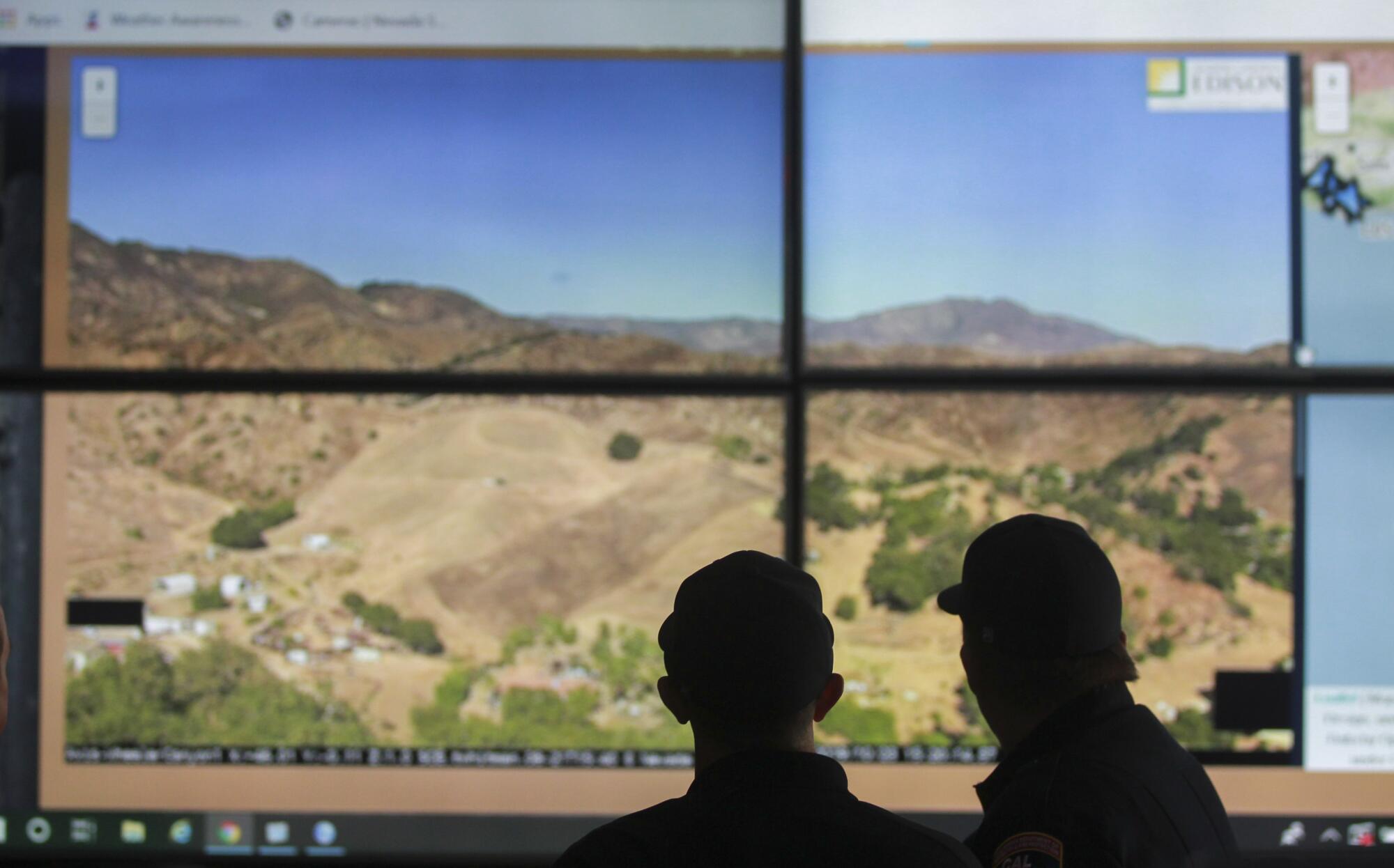 Cal Fire captains Kevin Cox, right, and Ryan Silva look at a screen as they demonstrate the use of wildfire surveillance cameras, mounted on various mountain tops in San Diego County, while in the Cal Fire emergency command center at the Cal Fire San Diego Unit Headquarters on Wednesday, October 23, 2019 in El Cajon, California.