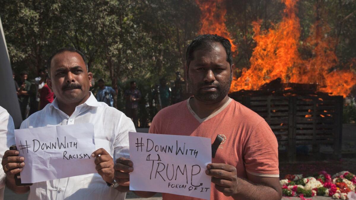 On Feb. 28 in Hyderabad, India, two men hold placards in front of the cremation pyre of Srinivas Kuchibhotla, a 32-year-old engineer who was killed in an apparently racially motivated shooting at an Olathe, Kansas, bar.